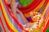 Fototapeta Natura - Young beautiful girl sleeping in a hammock with bare feet, relaxing and enjoying a lovely sunny summer day. Safety and happy childhood and leisure concept. Selective focus. Horizontal image.