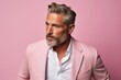 Portrait of a handsome mature man with grey hair and beard in a pink suit.