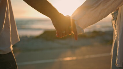 dating lovers holding hands on sunrise sea beach close up. couple touching arms