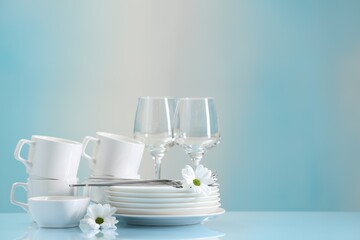 Sticker - Set of many clean dishware, cutlery, flowers and glasses on light blue table. Space for text