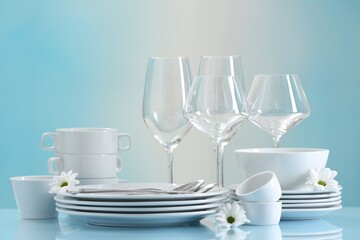 Wall Mural - Set of many clean dishware, cutlery, flowers and glasses on light blue table