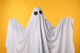 Fototapeta Kuchnia - Creepy ghost. Person covered with white sheet on yellow background