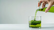 Woman hand pouring liquid chlorophyll in a glass cup