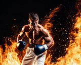 Fototapeta Sypialnia - Boxer in black boxing gloves fighting in fire