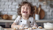 happy laughing little curly boy in a kitchen apron preparing cookies in a beautiful kitchen. Baking concept. Creative and happy childhood concept.