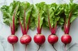 Fresh beetroots with vibrant green leaves and red stems on a marble background. Flat lay composition with copy space. Healthy eating and organic farming concept. 