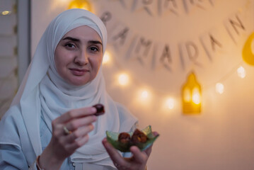 A happy Muslim woman eating dates for iftar to break fast during the holy month Ramadan concept of passing sharing food.