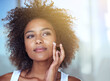 © Mapodile M/peopleimages.com - African woman, skincare and cream in bathroom for beauty, wellness and afro in home to start morning routine. Girl, person and serum for cosmetics, change and transformation with face in apartment