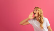 © Prostock-studio - blonde woman shouting announcing special offer against pink background
