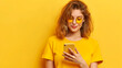 Woman holding phone against yellow background.