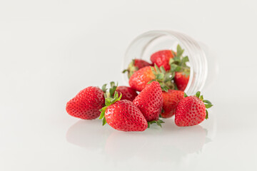 Wall Mural - ripe sweet fragrant strawberries pouring out of a glass goblet close up shallow depth of field