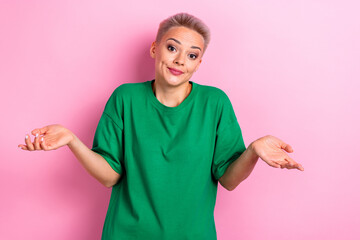 Wall Mural - Photo of confused unsure woman wearing green clothes showing gesture no answer shrugging shoulders isolated on pink color background