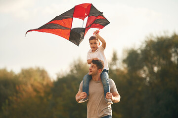 Wall Mural - Fun with kite, sitting on the shoulders. Father and little son are playing outdoors