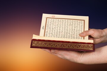Wall Mural - a man holding big holy Quran book in hands