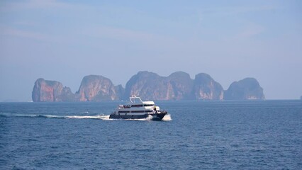 Wall Mural - Ferry floating in the sea in the background Maya Bay rocks, Phi Phi Don island, Andaman sea, Krabi