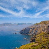 Fototapeta Las - calm sea bay with rocky coast under blue sky, summer sea vacation scene