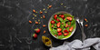 Summer vegetarian diet salad with strawberries, arugula, spinach, seeds and nuts in a bowl on a black stone background. Top view, flat lay, banner.