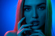Portrait of attractive, sensual, beautiful young woman with blonde hair, plump lips and perfect skin against blue background in neon light. Concept of natural beauty, cosmetology, cosmetics, skin care