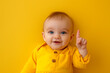 © UrbanOrigami - Happy Toddler Giving Thumbs Up on a Yellow Background