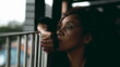 One sad pensive black middle-aged woman gazing at view from balcony in deep melancholic contemplation. Close-up face of an African American lady feeling lost in thought, pondering life's challenges