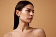Close up photo of young beautiful female woman with bare shoulders looking away against sandy color studio background. Concept of beauty, spa procedures, dermatology treatments, cosmetology care.