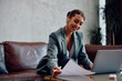 © Drazen - Happy businesswoman analyzing reports during conference call in hotel lobby.