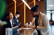 © Drazen - Black man filing registration paperwork at hotel front desk.