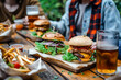 Casual Outdoor Dining with Gourmet Burgers, Fries, and Beer on Wooden Table
