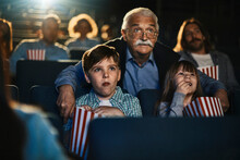 Grandfather and grandchildren watching film in movie theater