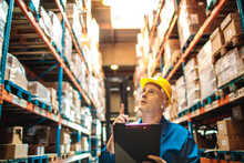Mature warehouse manager with clipboard checking inventory