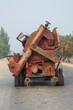 old rusty rice thresher on road with tractor