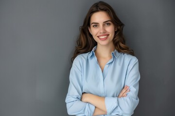 Wall Mural - Happy young smiling confident professional business woman wearing blue shirt, pretty stylish female executive looking at camera, standing arms crossed isolated on gray background