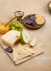 Wall Mural - Cheese on a wooden board next to fruit on a beige background