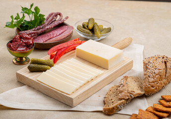 Wall Mural - Cheese on a wooden board next to fruit on a beige background