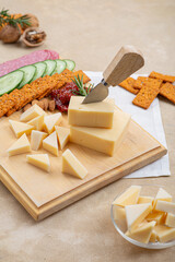 Wall Mural - Cheese on a wooden board next to fruit on a beige background