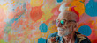 Portrait of an elderly caucasian man with bright mohawk-colored hair and sunglasses on the background of an abstract painting, summer brightness