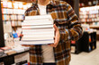© ADDICTIVE STOCK - Person holding a stack of books at a bookstore