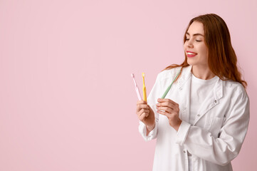 Canvas Print - Female dentist with toothbrushes on pink background. World Dentist Day