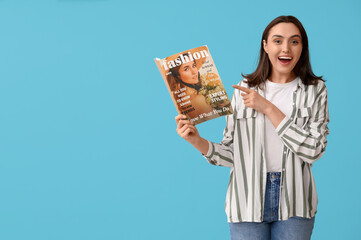 Poster - Young woman pointing at fashion magazine on blue background