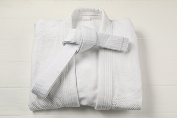 White karate belt and kimono on wooden background, top view