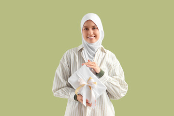 Wall Mural - Young Muslim woman with gift box on green background. Ramadan celebration