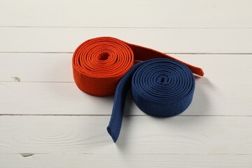 Orange and blue karate belts on wooden background. Martial arts uniform