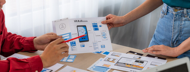 Panorama banner of startup UX developer or company employee design user interface or UI prototype for mobile application or website software with software display on laptop monitor in office. Synergic