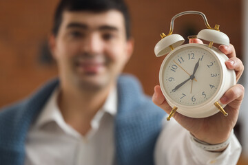 Canvas Print - Young businessman with alarm clock in office, closeup