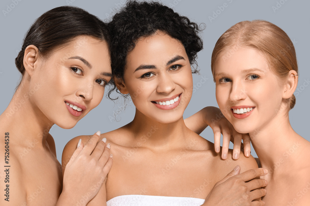 Beautiful young women hugging on grey background, closeup