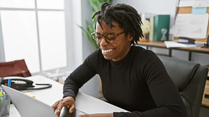 Canvas Print - Burst of laughter, joyful, young black woman with dreadlocks, cracking up hard at a funny joke while working on laptop in office interior.