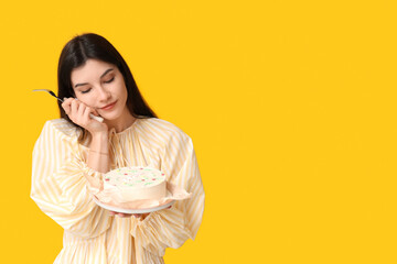 Wall Mural - Beautiful young woman with sweet bento cake and fork on yellow background. International Women's Day