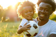 African father and son enjoying day in the park with soccer ball. Casual Father's Day conceptual portrait