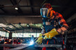 © Zamrznuti tonovi - Young man welding a piece of metal while making a metal construction.