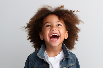 Wall Mural - Studio portrait. Funny little mixed race boy laughing on light background. Generative AI.